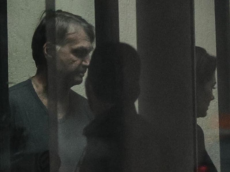 Ex-presidente Jair Bolsonaro é visto através do vidro da sede da Polícia Federal. - Gabriela Biló/Folhapress