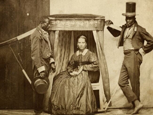 Senhora em uma liteira e dois homens escravizados na Bahia em 1880. - Instituto Moreira Salles