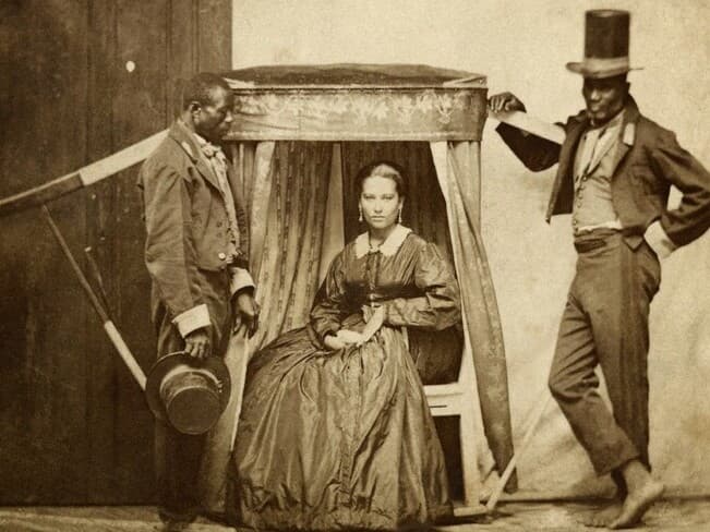 Senhora em uma liteira e dois homens escravizados na Bahia em 1880. - Instituto Moreira Salles